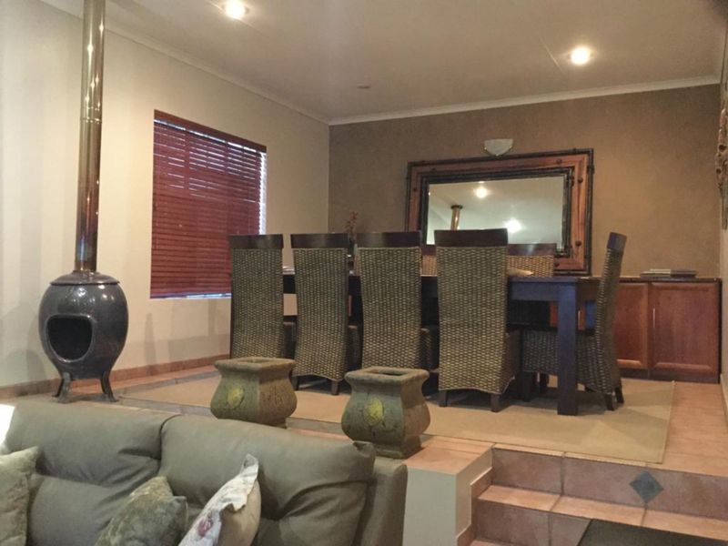Open plan living and dining area featuring a raised dining platform, tiled flooring, and a distinctive freestanding fireplace.