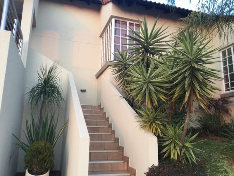 Exterior view of the townhouse entrance featuring a tiled staircase with concrete balustrades and security-barred windows.