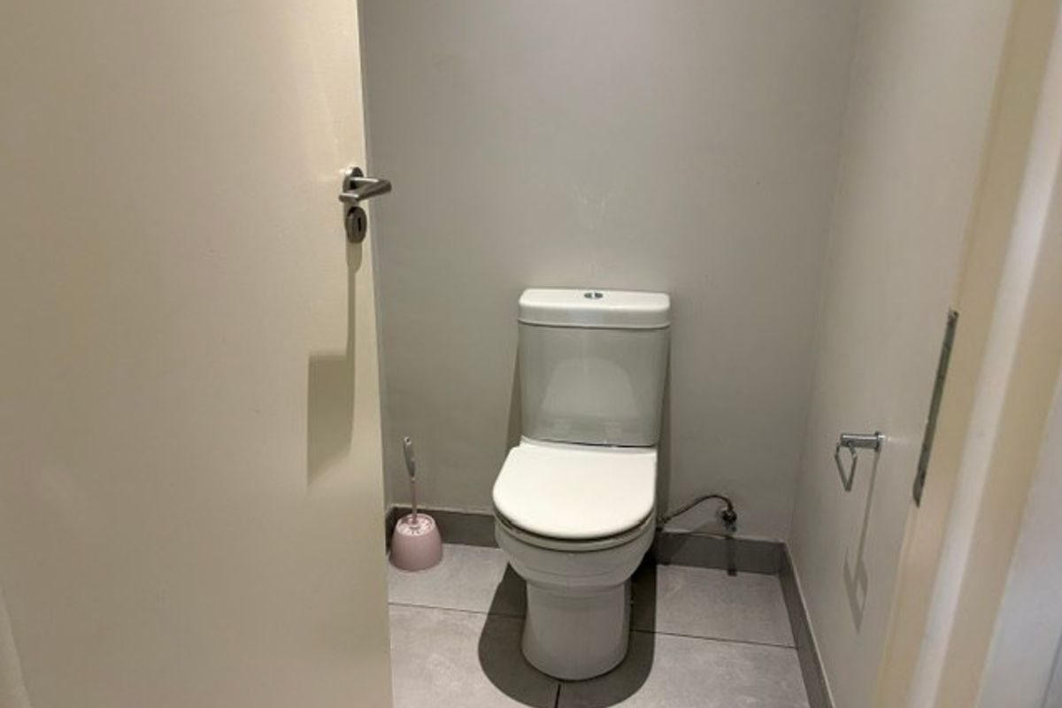 A compact guest bathroom featuring a modern toilet and neutral floor tiling.