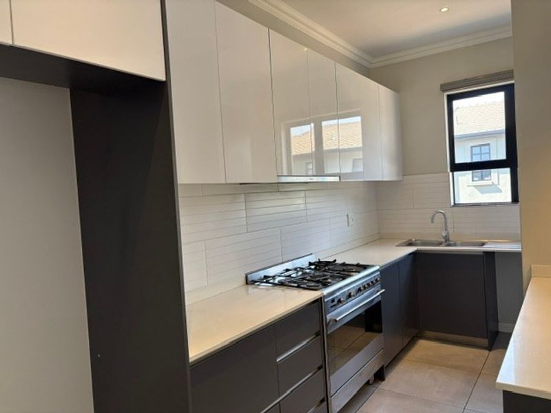 Modern kitchen featuring high-gloss cabinetry, stone countertops, subway tile backsplash, gas hob, and built-in oven with a double sink.