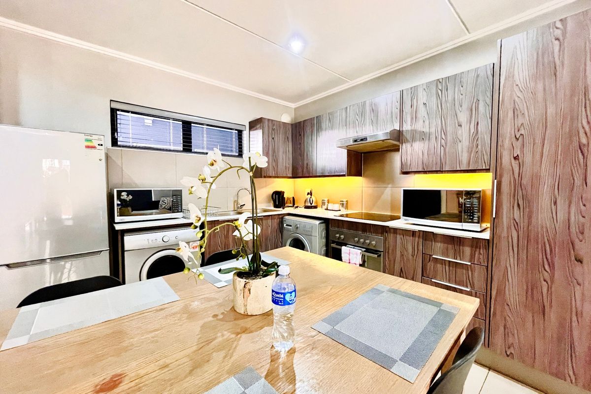 Modern kitchen featuring wood-grain cabinetry, integrated appliances, tiled backsplash, and under-cabinet lighting, providing a functional and stylish cooking space.