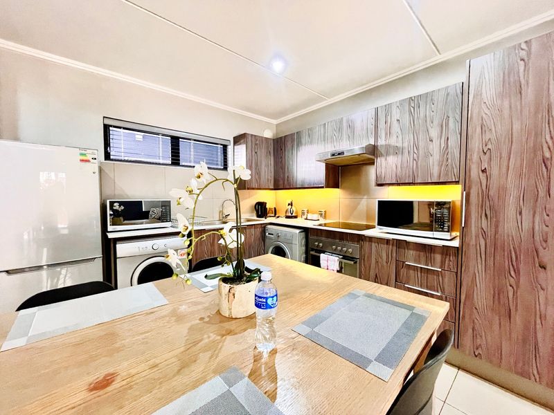 Modern kitchen featuring wood-grain cabinetry, integrated appliances, tiled backsplash, and under-cabinet lighting, providing a functional and stylish cooking space.