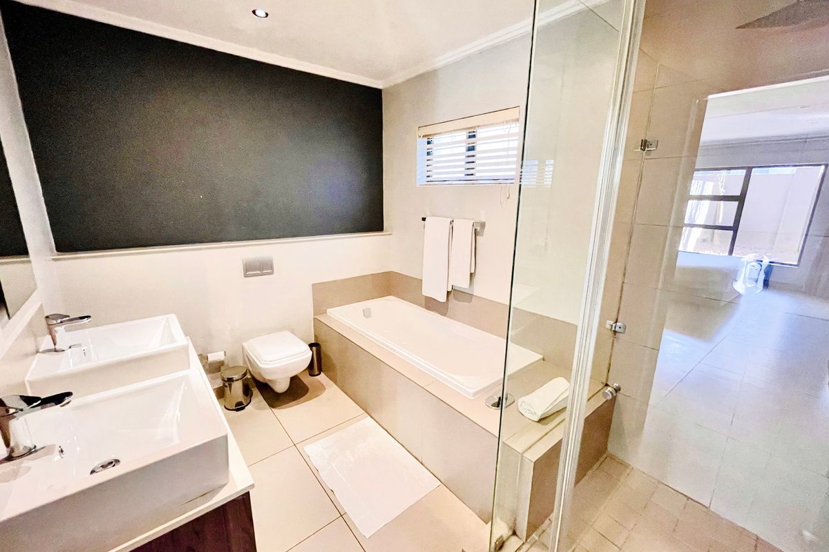 Modern bathroom featuring a double vanity, built-in bathtub, and a separate glass-enclosed shower with a rain shower head.