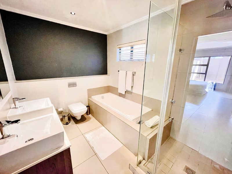 Modern bathroom featuring a double vanity, built-in bathtub, and a separate glass-enclosed shower with a rain shower head.