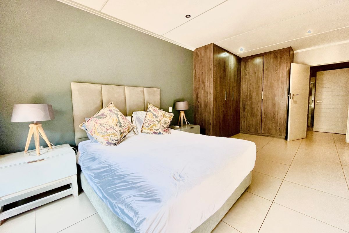 Spacious bedroom featuring neutral tiled flooring, built-in wooden cupboards, and modern recessed lighting, creating a clean and functional living space.