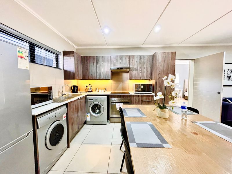 Modern kitchen featuring wood-grain cabinetry, integrated appliances, tiled flooring, and under-cabinet lighting, providing a functional and contemporary cooking space.