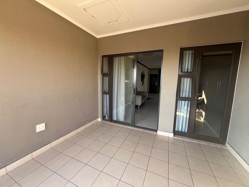 A covered balcony area featuring tiled flooring and sliding glass doors providing access to the interior living space.