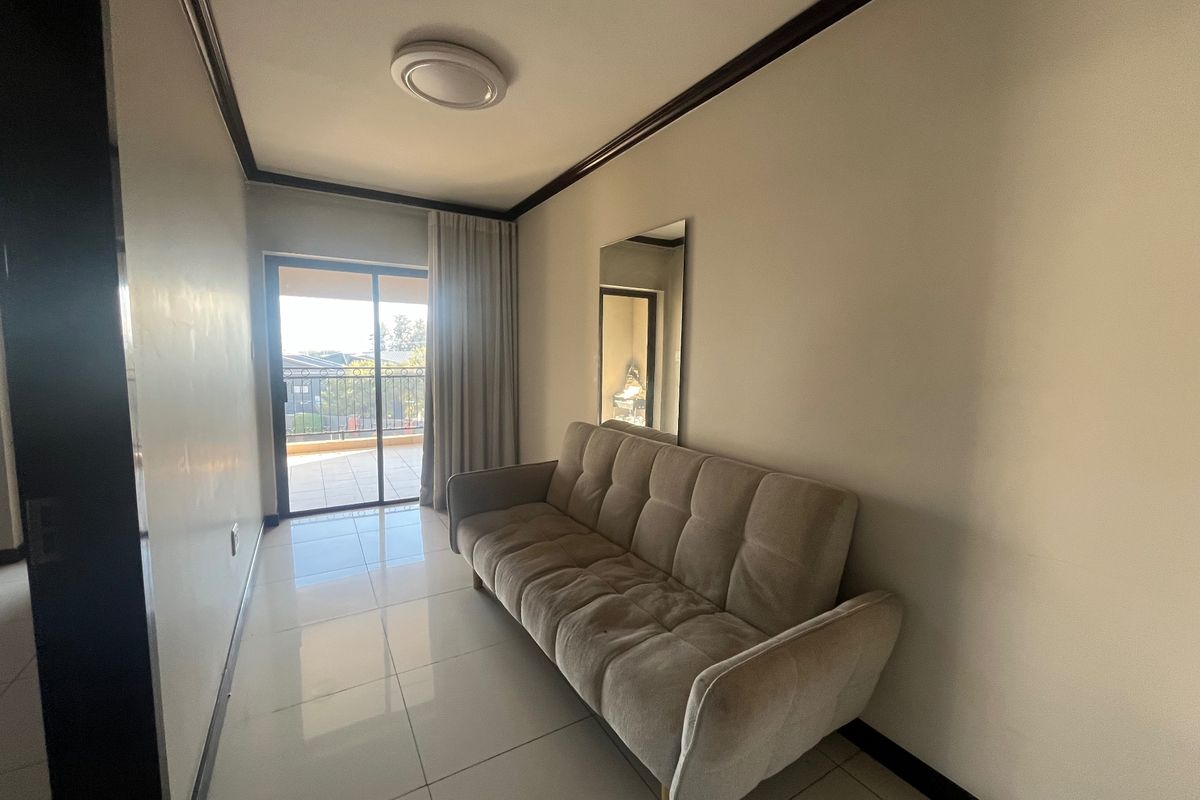 A living room featuring tiled flooring, crown molding, and a sliding glass door providing access to an outdoor balcony area.