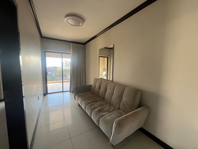 A living room featuring tiled flooring, crown molding, and a sliding glass door providing access to an outdoor balcony area.