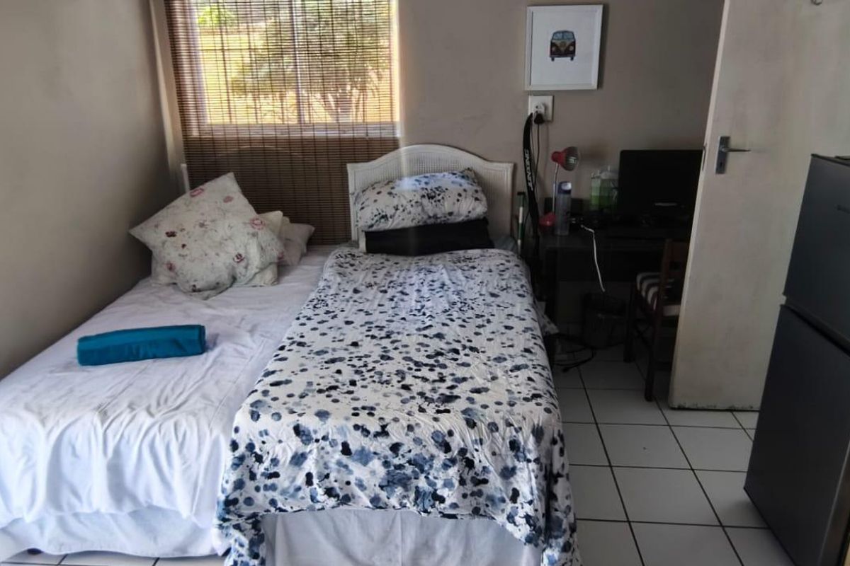 A compact bedroom featuring tiled flooring and a window, providing a functional living space.