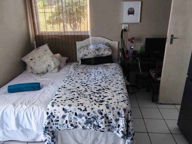 A compact bedroom featuring tiled flooring and a window, providing a functional living space.