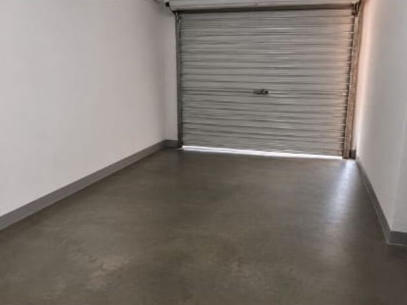 A clean, empty garage space featuring smooth concrete flooring and a secure roller shutter door.