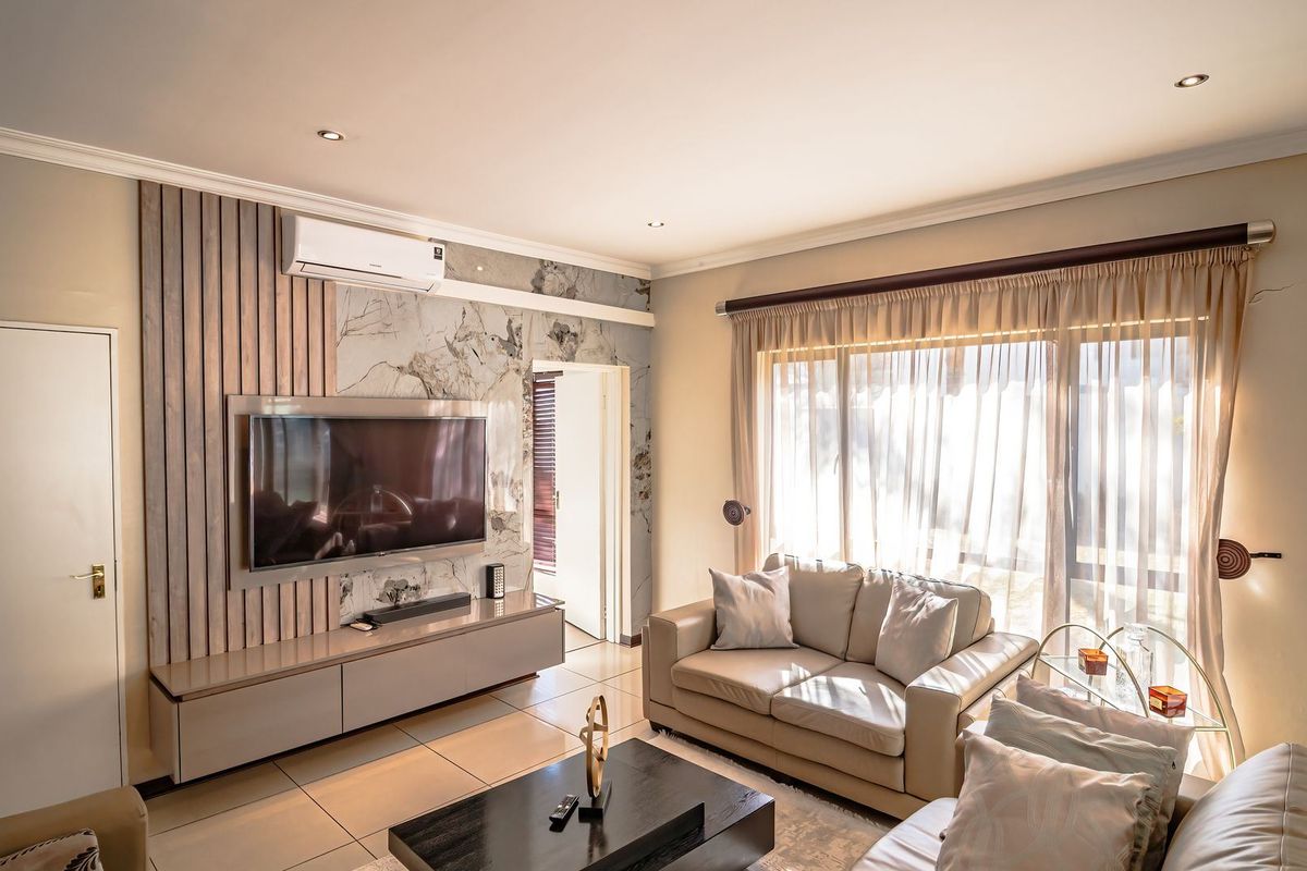 Modern living room featuring a stylish timber slat and marble-look feature wall, built-in media console, tiled flooring, and large sliding doors for natural light.