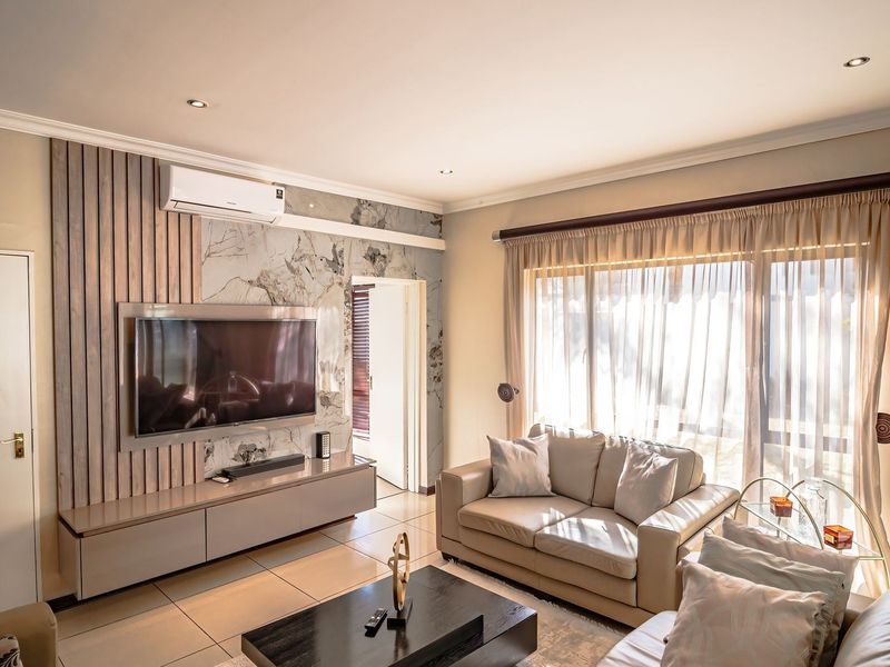 Modern living room featuring a stylish timber slat and marble-look feature wall, built-in media console, tiled flooring, and large sliding doors for natural light.