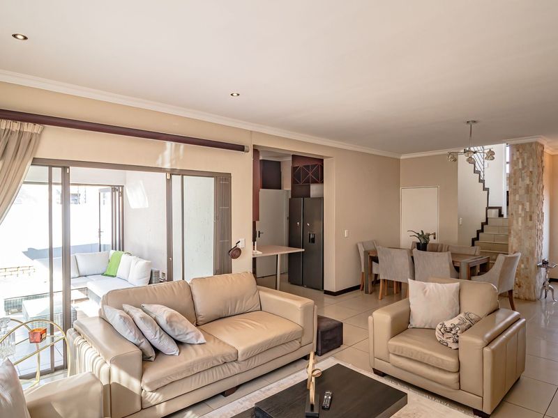 Spacious open-plan living and dining area featuring tiled floors, recessed lighting, and a distinctive stone-clad pillar, with seamless access to the outdoor patio.