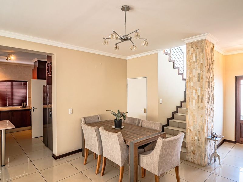 Open-plan living and dining area featuring a striking stone-clad pillar, tiled flooring, and a seamless transition to the adjacent kitchen space.
