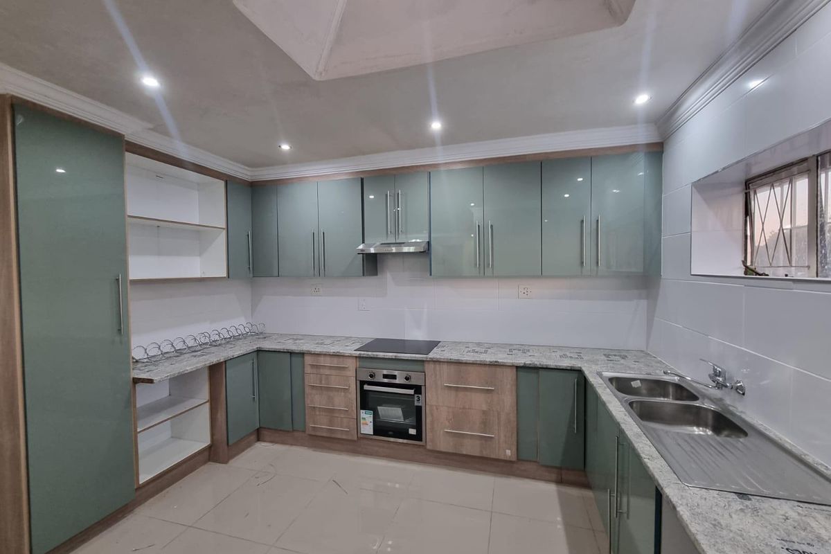 Modern kitchen featuring high-gloss cabinetry, granite countertops, integrated oven and hob, and a double stainless steel sink with tiled flooring.