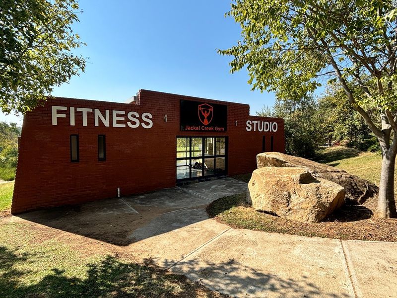Exterior view of the Jackal Creek Gym facility featuring a brick facade and landscaped surroundings.