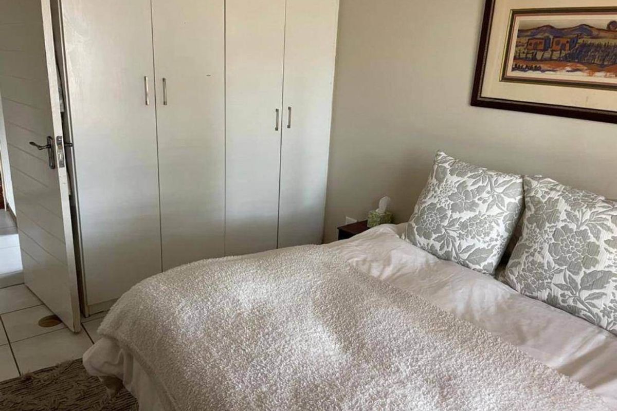 A functional bedroom featuring built-in cupboards and tiled flooring, providing a practical and comfortable living space.