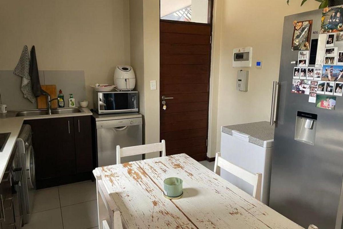 A functional kitchen area featuring built-in cabinetry, a stainless steel sink, and tiled flooring, with direct access to an exterior door.