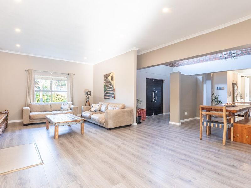 Spacious open-plan living and dining area featuring modern laminate flooring, exposed brick accents, a wood-burning stove, and a well-integrated kitchen.