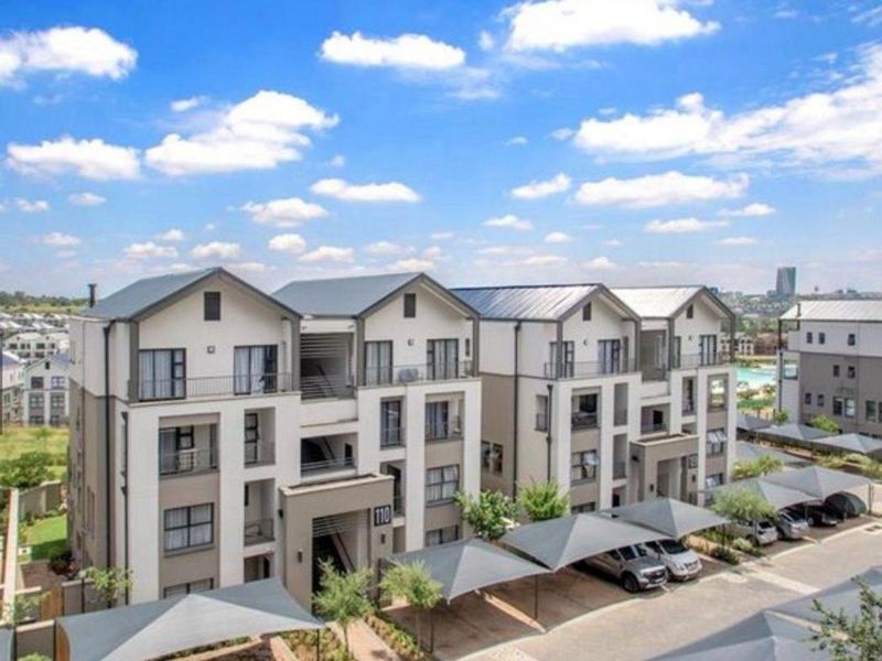 A multi-story apartment complex featuring modern architectural design, private balconies, and dedicated covered parking bays within a well-maintained residential estate.