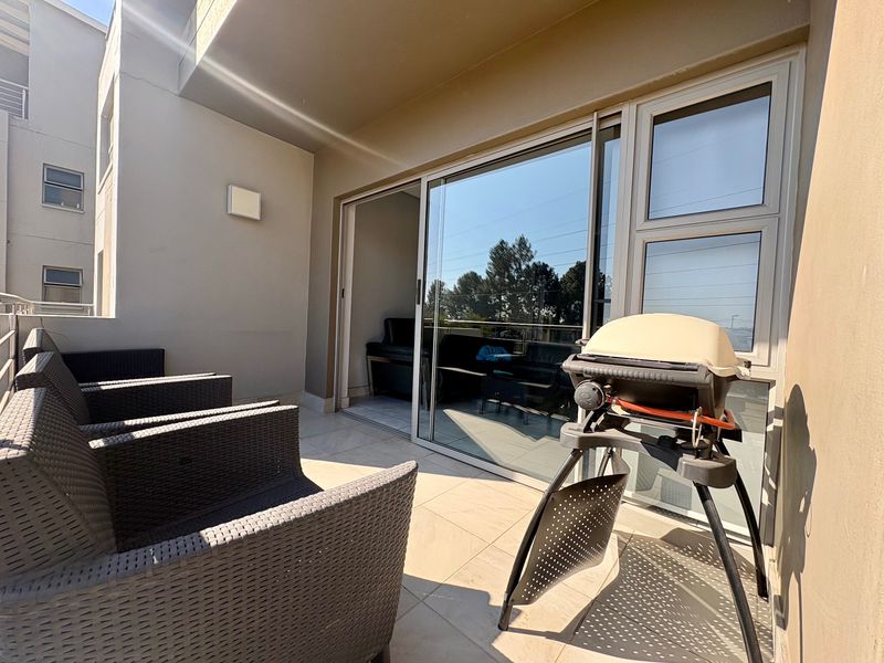 A covered balcony featuring tiled flooring and large sliding glass doors providing access to the interior living space.