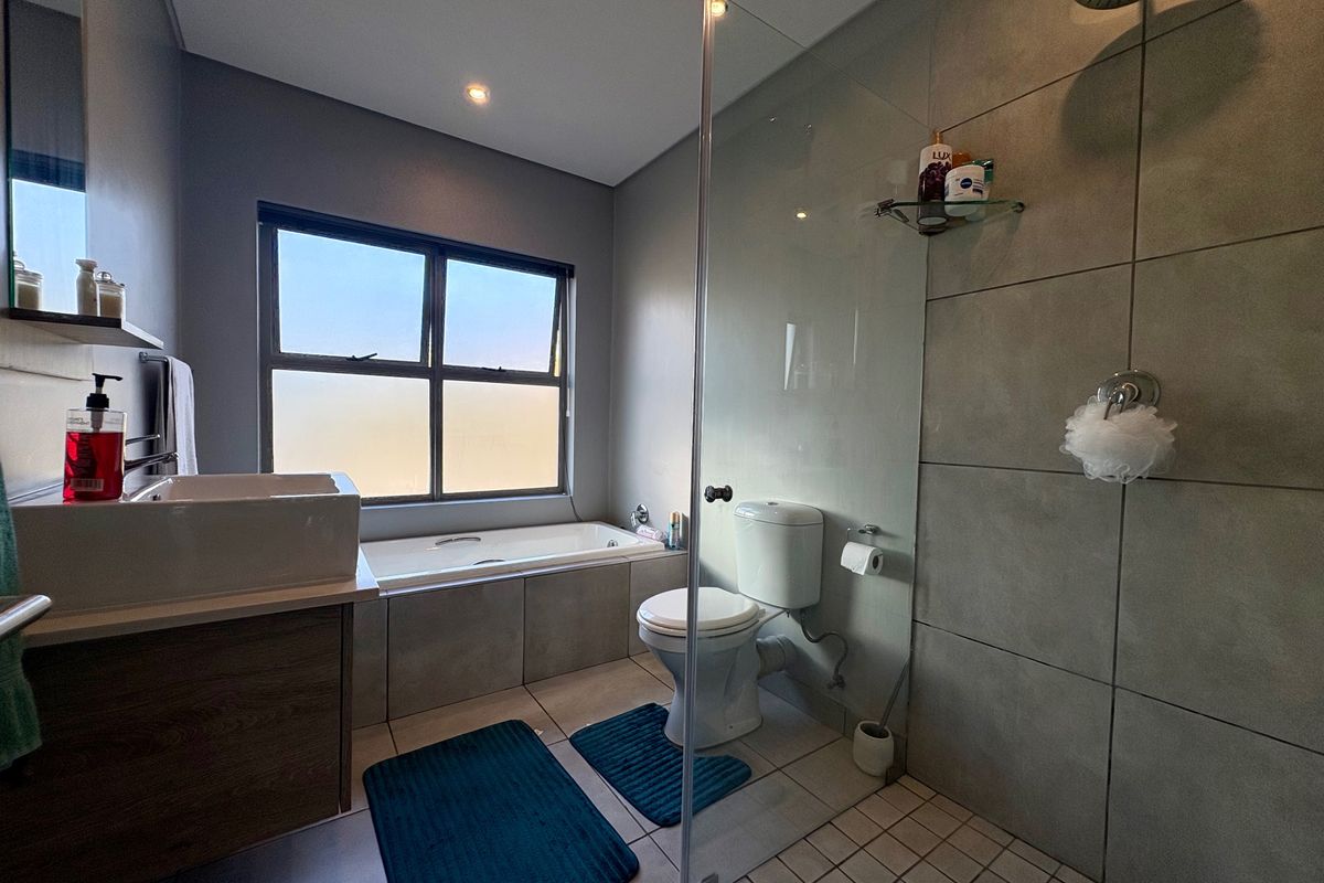 Modern bathroom featuring a built-in bathtub, a glass-enclosed shower with a rain shower head, and a contemporary vanity basin.