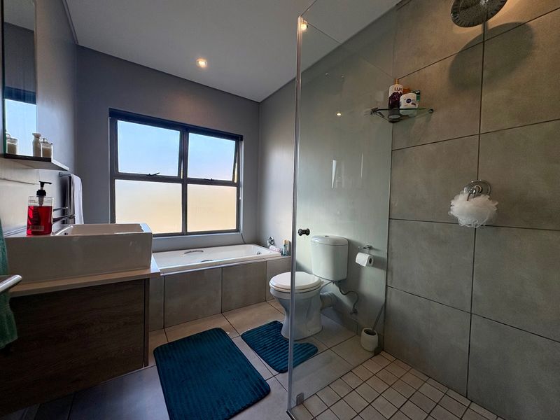 Modern bathroom featuring a built-in bathtub, a glass-enclosed shower with a rain shower head, and a contemporary vanity basin.