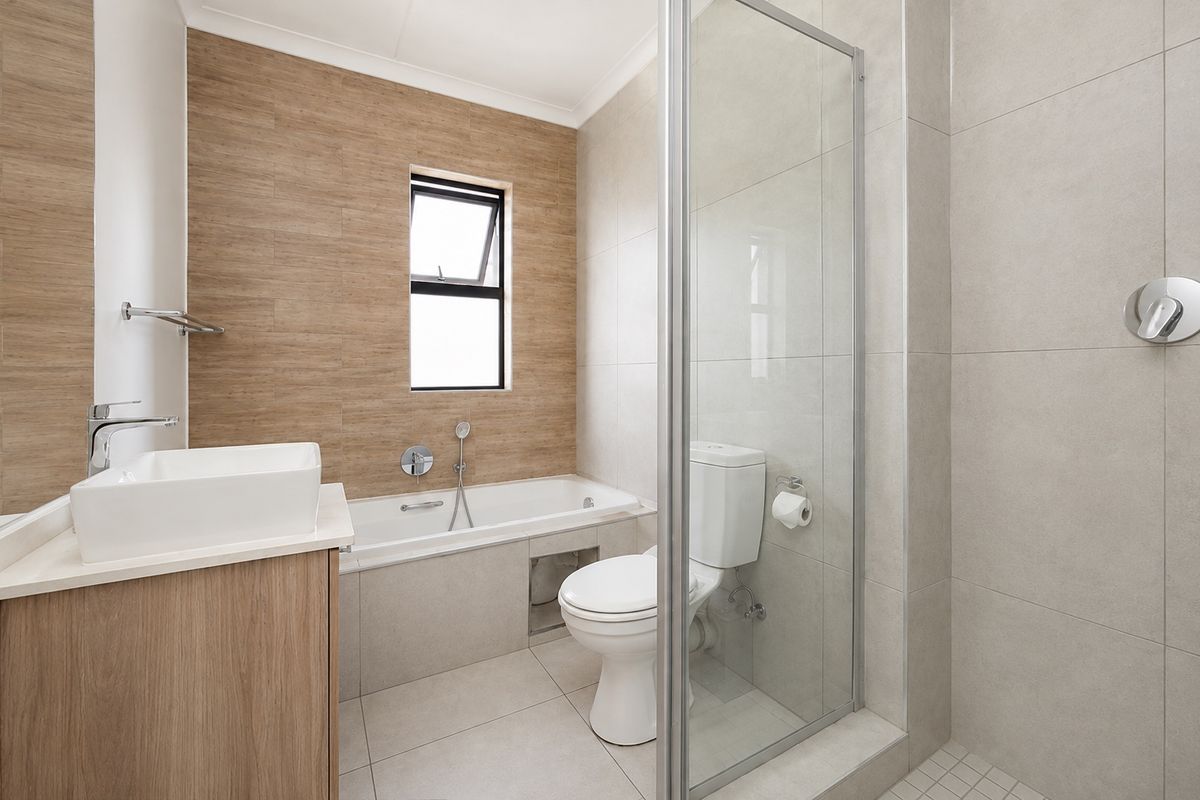 Modern bathroom featuring a built-in bathtub, separate glass-enclosed shower, vanity with vessel sink, and neutral floor-to-ceiling tiling.