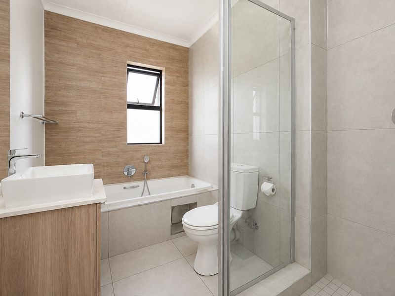 Modern bathroom featuring a built-in bathtub, separate glass-enclosed shower, vanity with vessel sink, and neutral floor-to-ceiling tiling.