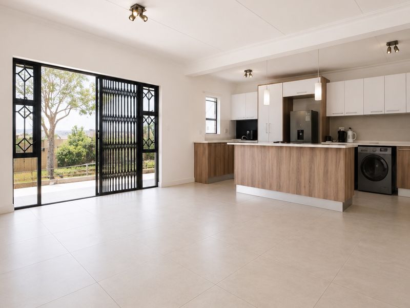 Spacious open-plan living and kitchen area featuring modern cabinetry, a central island, tiled flooring, and large sliding doors leading to an outdoor space.