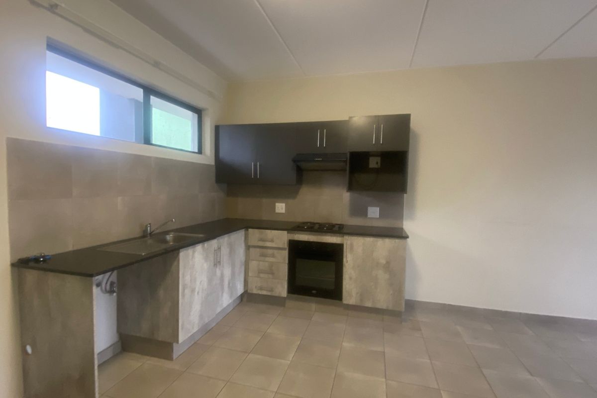 A clean, modern kitchen featuring built-in cabinetry, dark countertops, a gas hob, and an integrated oven, offering a functional and well-maintained cooking space.