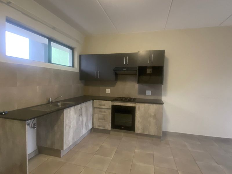 A clean, modern kitchen featuring built-in cabinetry, dark countertops, a gas hob, and an integrated oven, offering a functional and well-maintained cooking space.