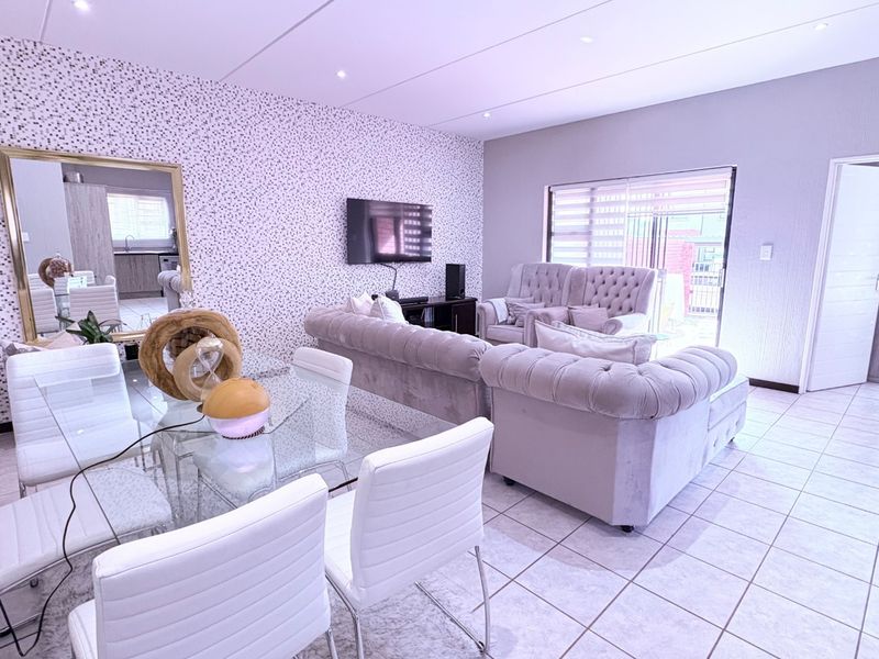 Spacious open-plan living and dining area featuring tiled flooring, recessed lighting, and direct access to an outdoor patio through sliding glass doors.