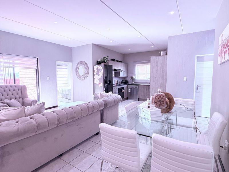 Spacious open-plan living and dining area featuring tiled floors, recessed lighting, and a modern kitchen with built-in cabinetry and integrated appliances.