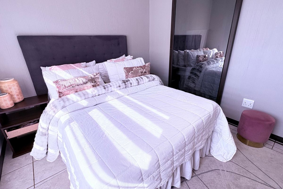 A well-maintained bedroom featuring tiled flooring and a large built-in wardrobe with mirrored doors.