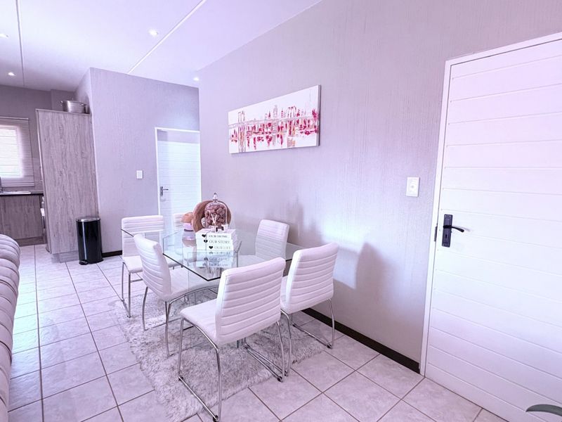 An open-plan living and dining area featuring tiled flooring, recessed lighting, and a functional kitchen space with built-in cabinetry.
