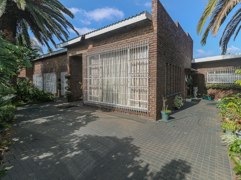 Front exterior view of a face brick house featuring paved driveway access and security bars on windows.