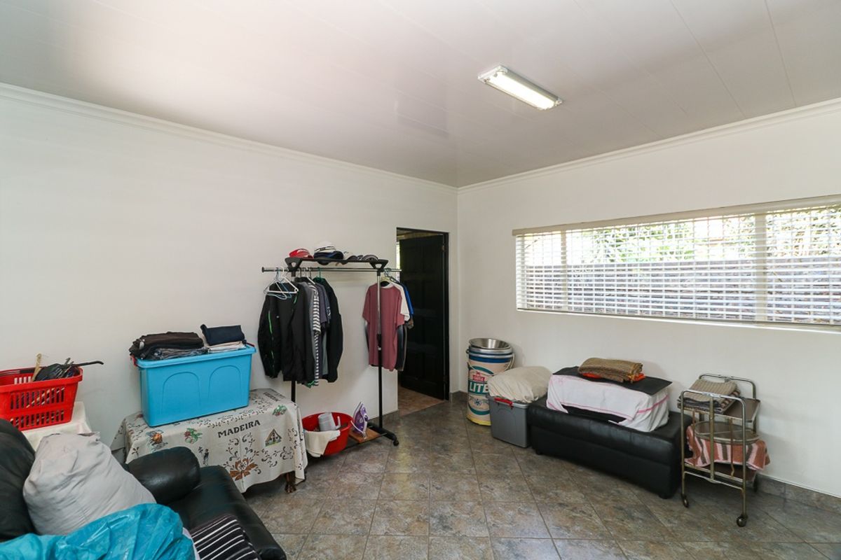 A functional bedroom space featuring tiled flooring, venetian blinds, and a standard ceiling light fixture.