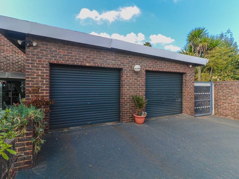 A double garage featuring dark roller doors, face brick construction, and a paved driveway, providing secure off-street parking.
