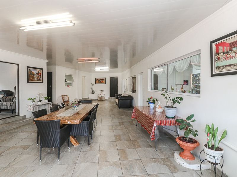 Spacious open-plan living and dining area featuring neutral tiled flooring and bright overhead lighting, offering a versatile layout for family gatherings.