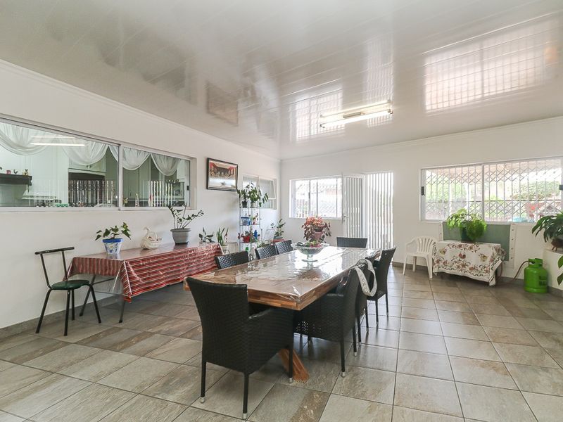 Spacious dining area featuring tiled flooring, a glossy ceiling finish, and an internal window providing a view into the adjacent kitchen space.