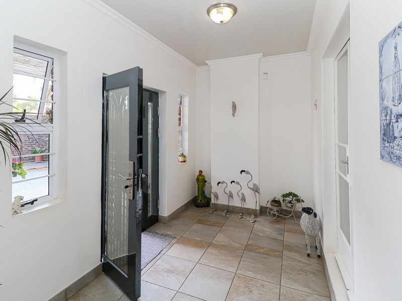 A bright and clean entrance hall featuring neutral tiled flooring, a glass-panelled door, and crisp white walls, providing a welcoming transition into the home.