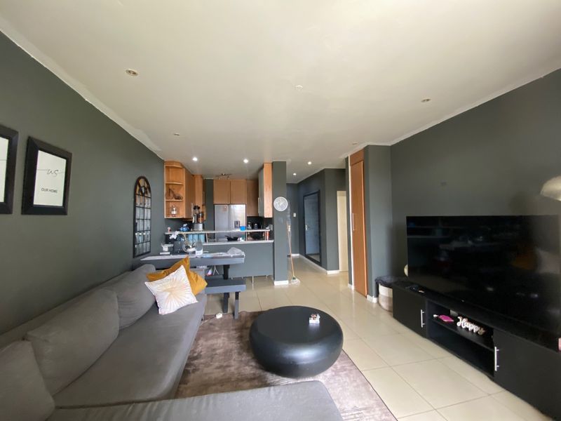 Open-plan living area featuring tiled flooring, recessed lighting, and a functional kitchen with breakfast counter and built-in cabinetry.