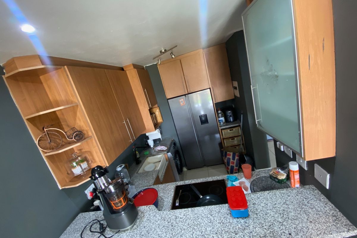 Compact kitchen featuring wooden cabinetry, granite countertops, and a built-in hob, offering a functional layout with integrated storage solutions.