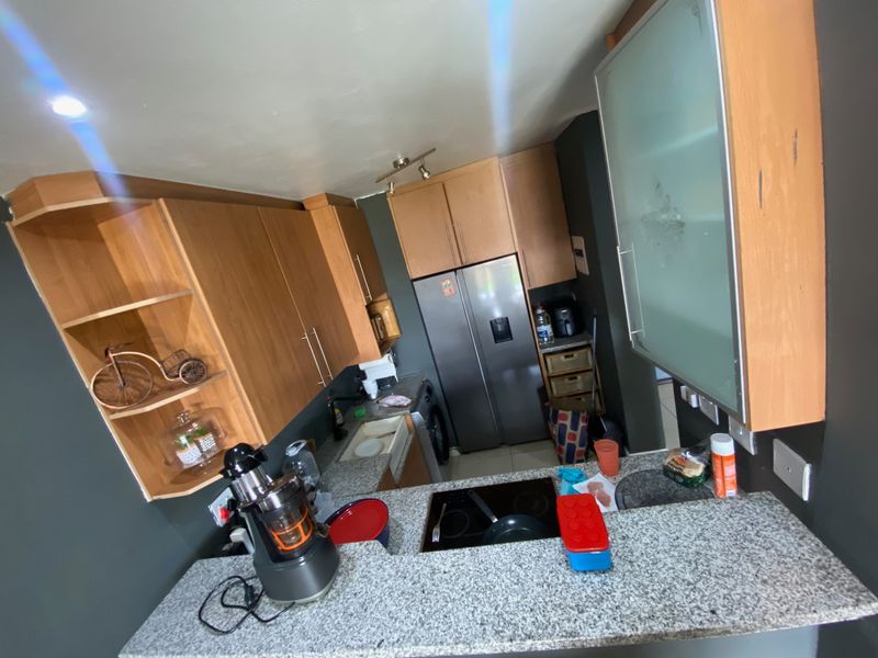 Compact kitchen featuring wooden cabinetry, granite countertops, and a built-in hob, offering a functional layout with integrated storage solutions.