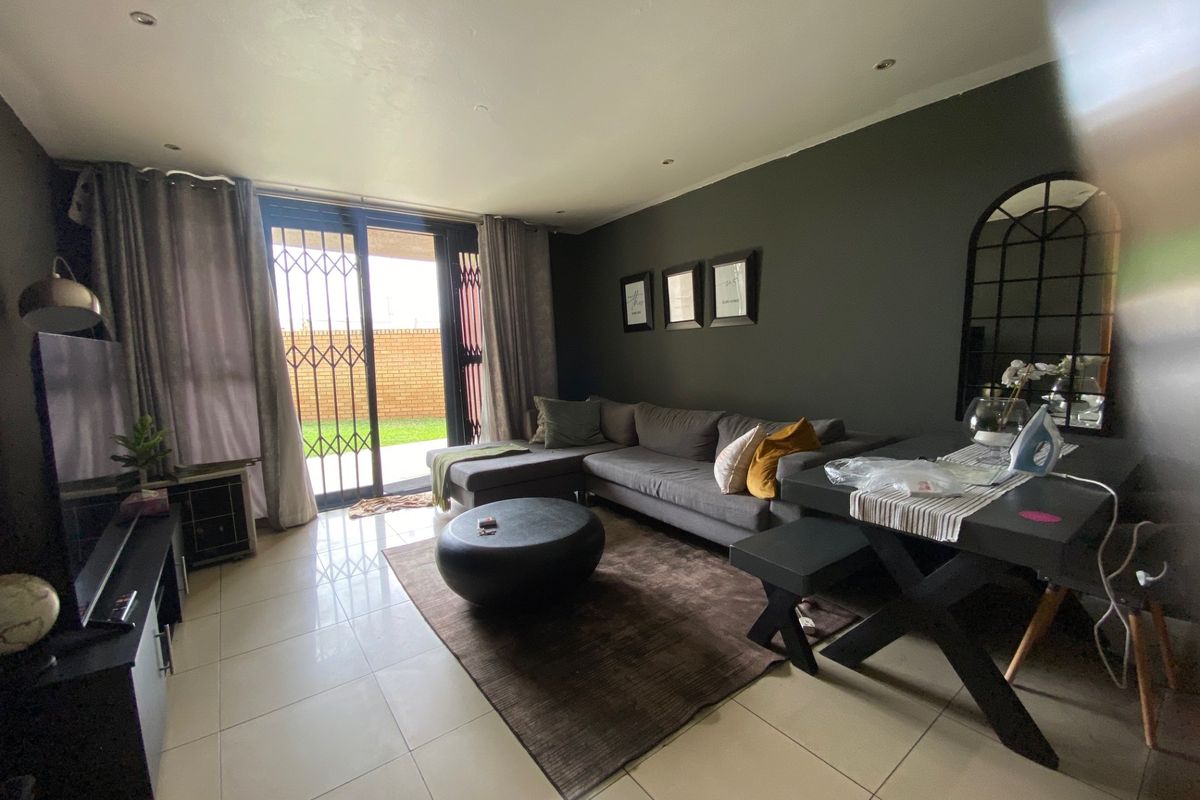 A well-maintained living room featuring tiled flooring, recessed lighting, and a sliding glass door providing access to the outdoor area.