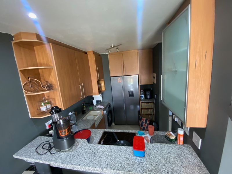 Compact kitchen featuring granite countertops, wooden cabinetry, and integrated appliances, offering a functional layout with a breakfast bar area.