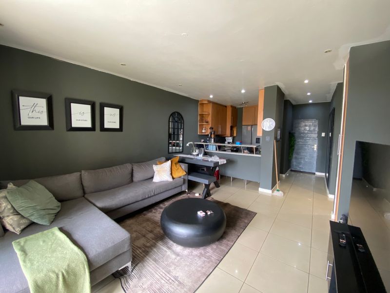 Open-plan living area featuring tiled flooring, recessed lighting, and a functional kitchen with breakfast counter and built-in cabinetry.